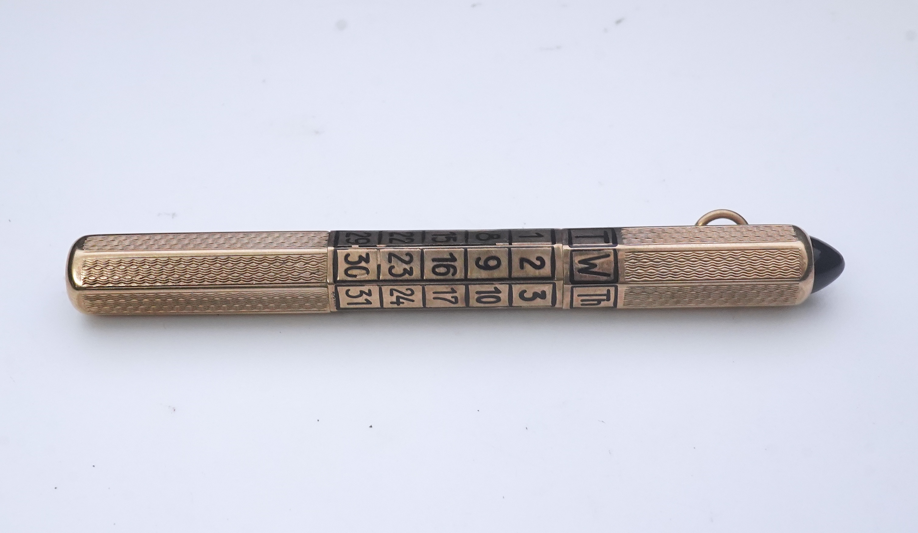 A gold calendar pencil and a gold pocket stamp dispenser